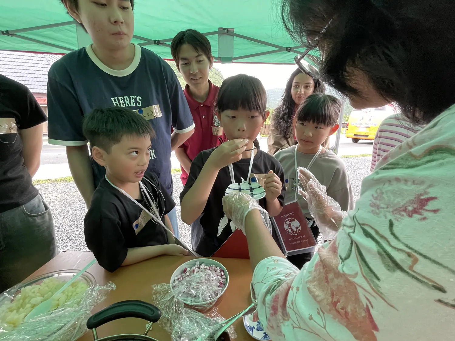 調理台の手元を子どもと留学生がのぞき込んでいる様子(MIYAMA EXPO 3rd)