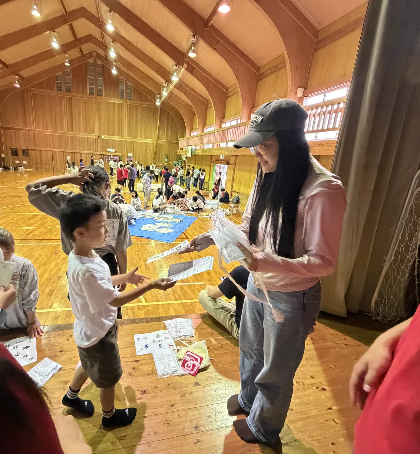 体験ブース — 舞台の上でプロフ帳を交換する子どもと留学生。